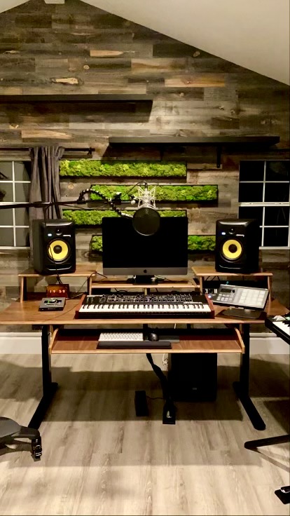 A home sound studio with wood slat walls is pictured with four moss panels hanging horizontally to reduce noise and enhance the woody aesthetic of the room.