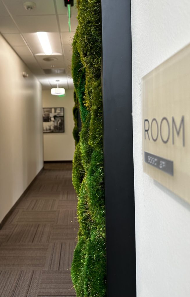 Pillow moss framed in a matte black frame hangs in a hallway of a care center.